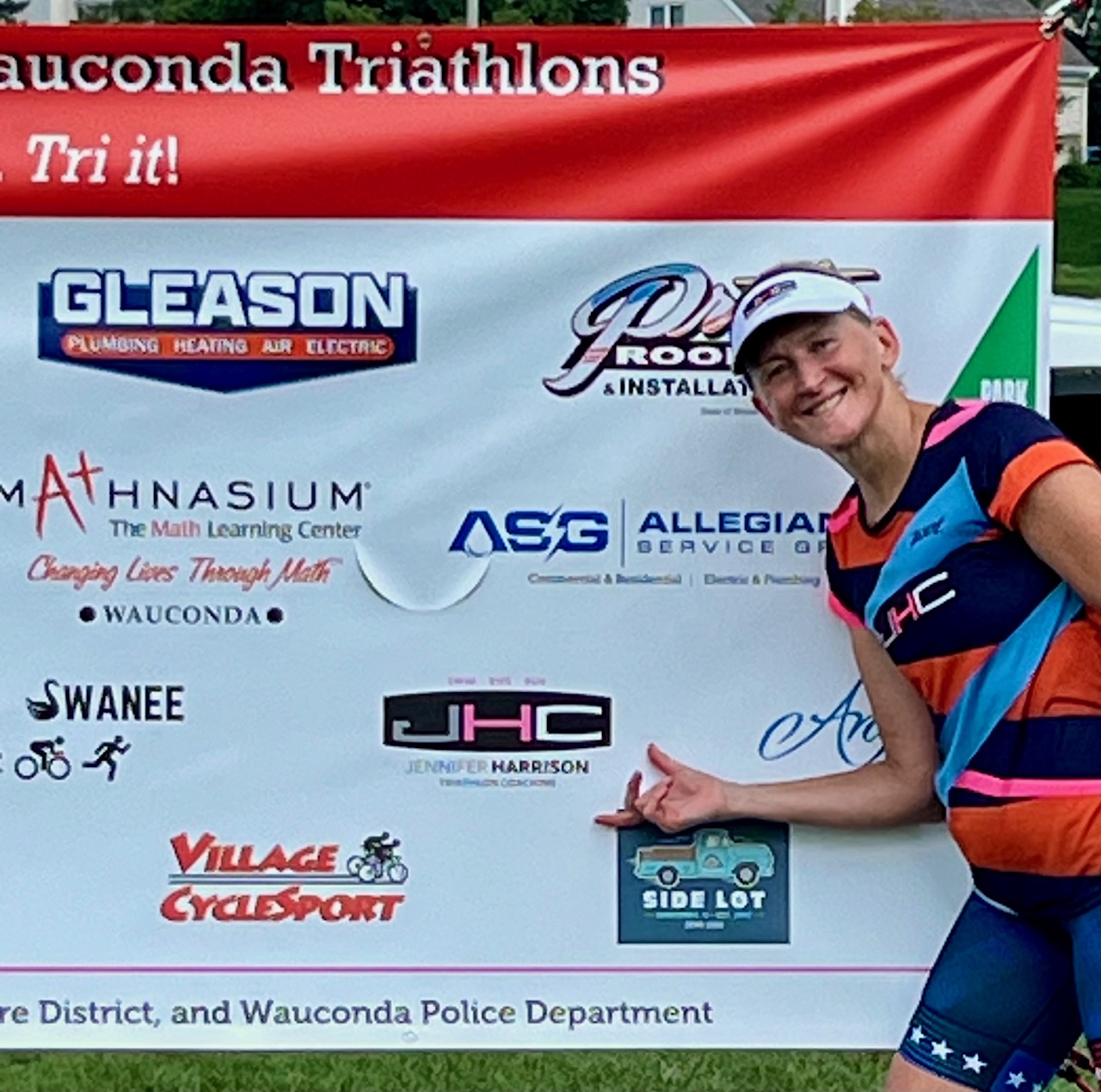 Jennifer Harrison beside the JHC Coaching logo on the Wauconda Triathlons sponsor banner